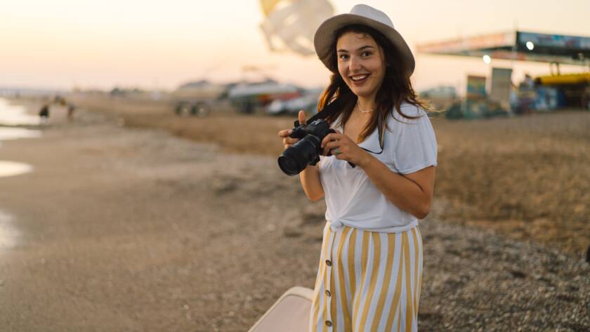 Traveling and photography. Young woman with a camera is photographed on the sea beach.