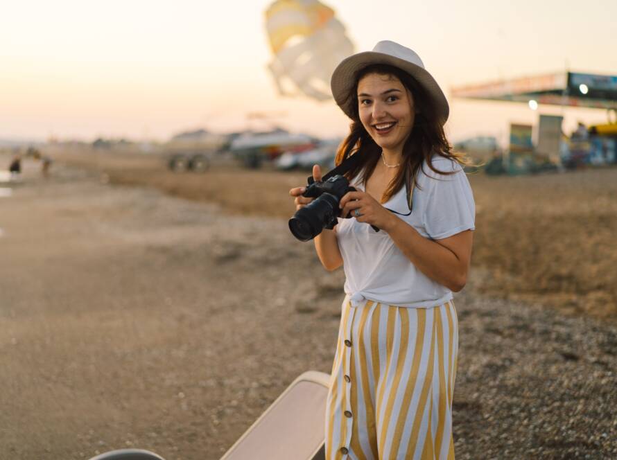 Traveling and photography. Young woman with a camera is photographed on the sea beach.